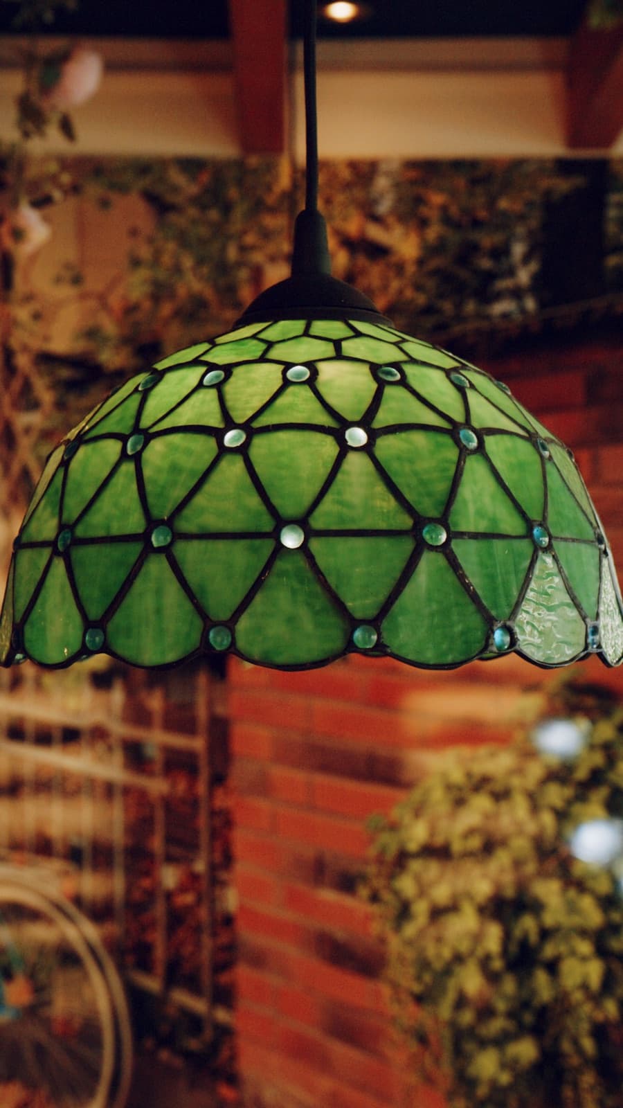 Grüne Tiffany-Lampe als Detail zwischen Pflanzen