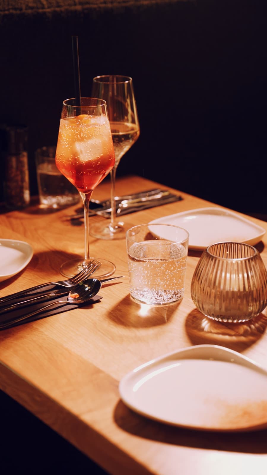 Gedeckter Tisch mit einem Glas Roséwein bei warmem Licht